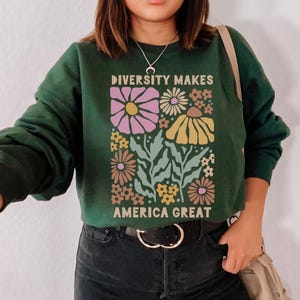 May include: A dark green sweatshirt with a floral design and the text "Diversity Makes America Great".