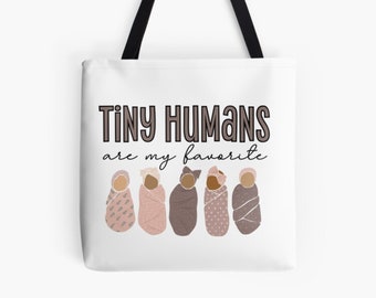 Puede incluir: Una bolsa de tela blanca con el texto "Tiny Humans are my favorite" en letras negras y marrones. Seis bebés de piel morena envueltos en mantas rosas con diferentes patrones están alineados debajo del texto.