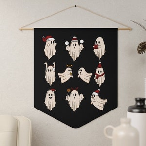 May include: A black fabric tapestry with a white ghost wearing a Santa hat and holding a candy cane. The tapestry features 12 different ghosts in various holiday poses.