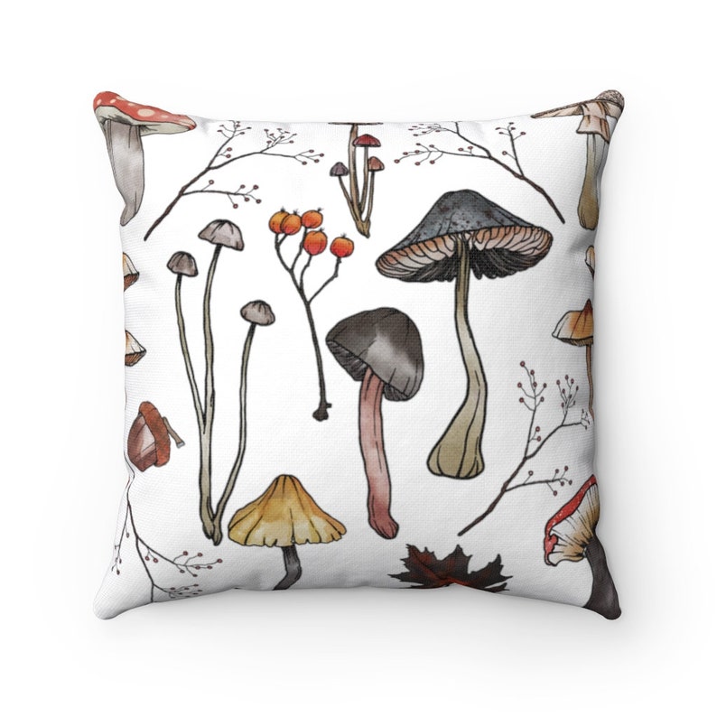 K&ouml;nnte beinhalten: Ein wei&szlig;es Kissen mit einem bunten Pilzmuster. Die Pilze sind im Aquarell-Stil gezeichnet und haben verschiedene Farben, darunter Rot, Orange, Braun und Grau. Das Kissen ist perfekt, um jedem Raum einen Hauch von Natur zu verleihen.