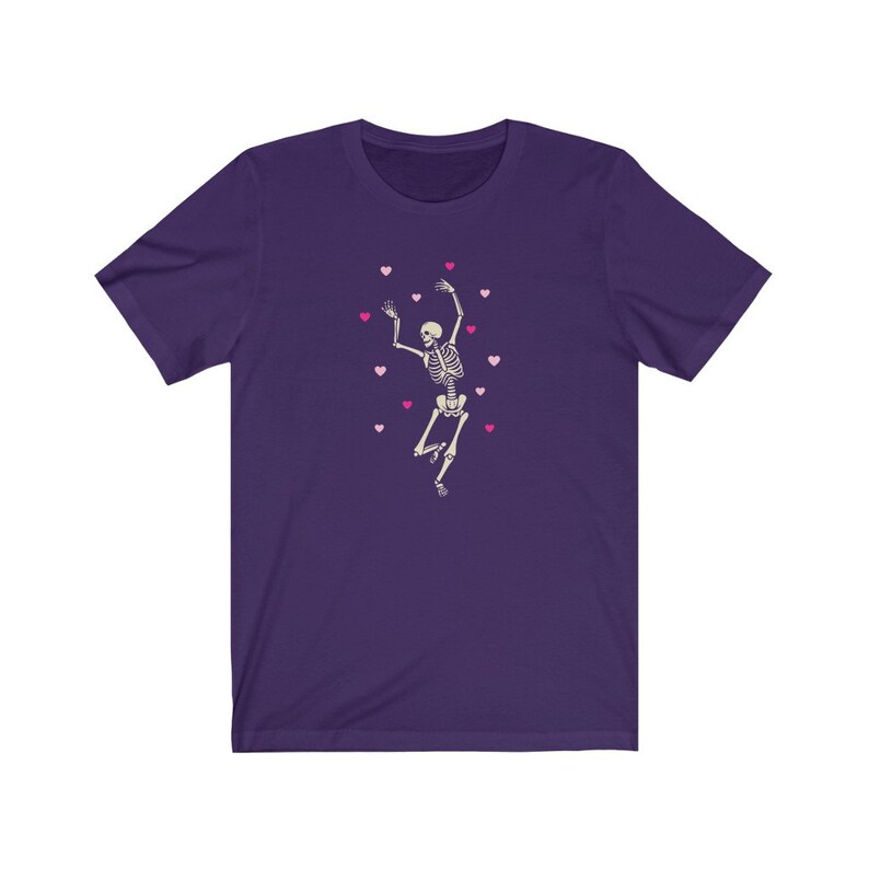 May include: Purple t-shirt with a white skeleton dancing and pink hearts scattered around it.