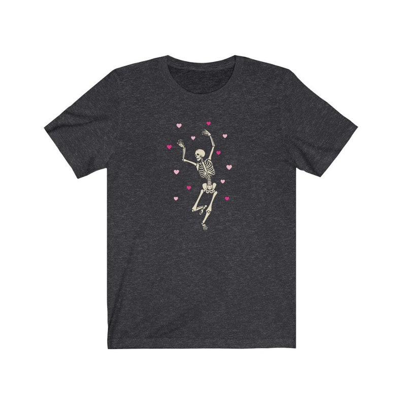 May include: A dark heather grey t-shirt with a skeleton dancing and surrounded by pink hearts.