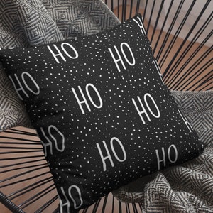 May include: Black and white throw pillow with a repeating pattern of "HO HO" text on a black background with white polka dots.