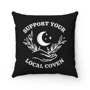 May include: Black throw pillow with white text that reads "Support Your Local Coven" and a crescent moon with stars above a hand holding a sprig of leaves.