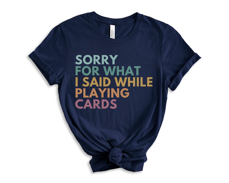 Puede incluir: Camiseta azul marino con el texto "SORRY FOR WHAT I SAID WHILE PLAYING CARDS" en degradado arco&iacute;ris.