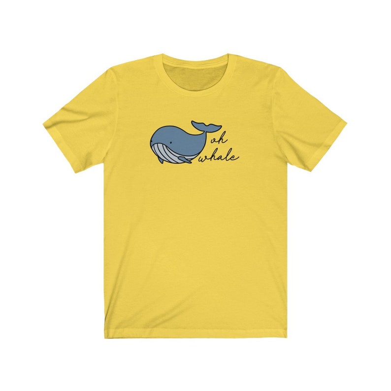 以下が含まれることがあります： 前面に青いクジラのイラストと「oh whale」という文字がプリントされた黄色のTシャツです。