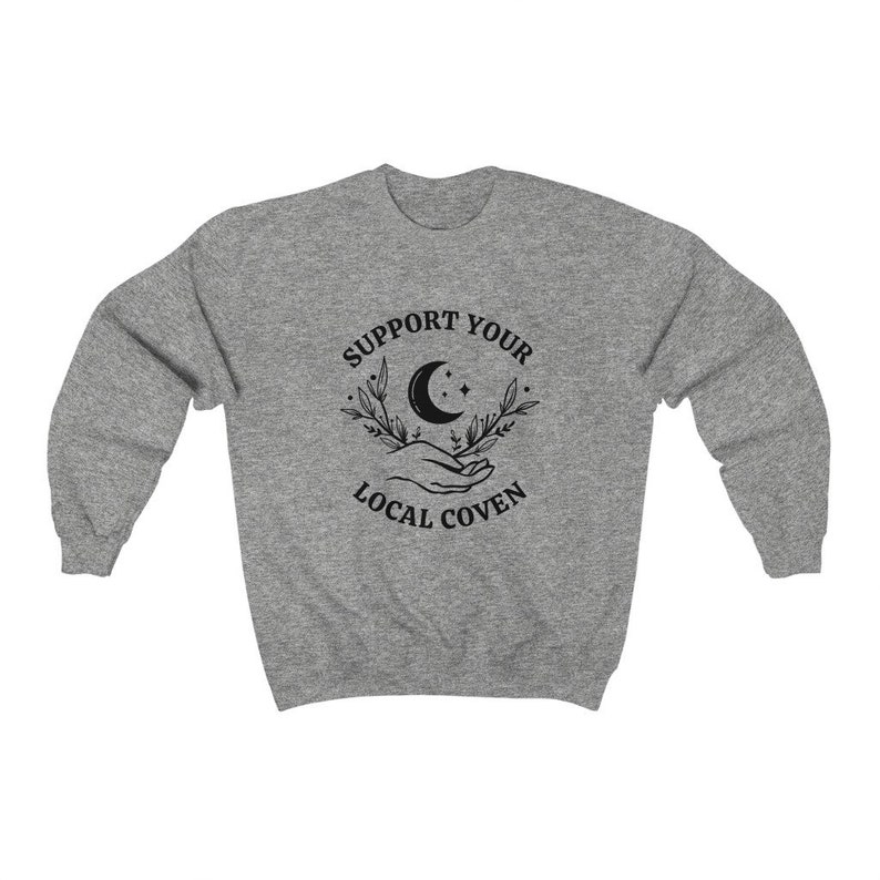 May include: Gray sweatshirt with a black graphic design that says "Support Your Local Coven" with a crescent moon, stars, and two hands holding the moon.