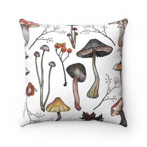K&ouml;nnte beinhalten: Ein wei&szlig;es Kissen mit einem Aquarellmuster aus Pilzen und Zweigen mit roten Beeren. Die Pilze sind in verschiedenen Formen und Gr&ouml;&szlig;en, einige mit roten H&uuml;ten und andere mit braunen H&uuml;ten.