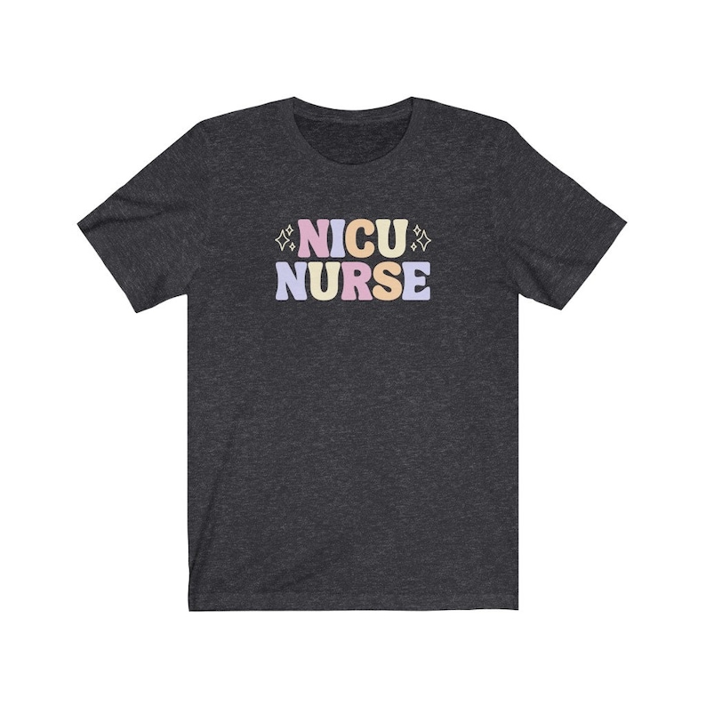Peut inclure: Un t-shirt gris fonc&eacute; chin&eacute; avec le texte "NICU NURSE" en lettres color&eacute;es. Les lettres sont dans un style de police r&eacute;tro avec un sch&eacute;ma de couleurs rose, jaune et bleu.