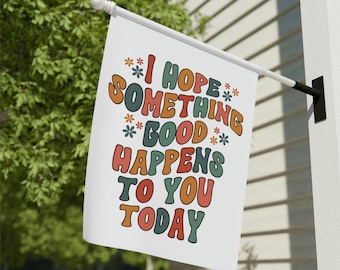 May include: A white flag with the text "I hope something good happens to you today" in colorful, retro-style lettering. The text is surrounded by small flower illustrations.