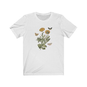 May include: White t-shirt with a floral design featuring yellow flowers and butterflies.