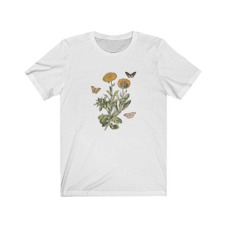 May include: White t-shirt with a floral design featuring yellow flowers and butterflies.
