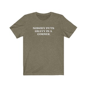 May include: A green t-shirt with the text "Nobody puts gravy in a corner" printed in white.