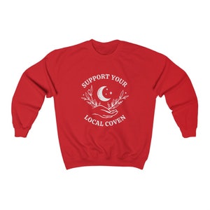 May include: Red sweatshirt with a white graphic design that says "Support Your Local Coven" with a crescent moon and stars.