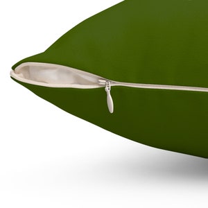 May include: A dark green pillow with a zipper closure. The zipper is visible and has a white pull tab.