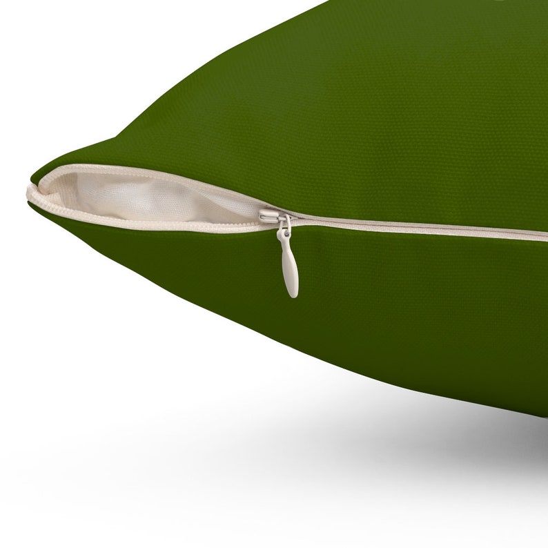 May include: A dark green pillow with a zipper closure. The zipper is visible and has a white pull tab.