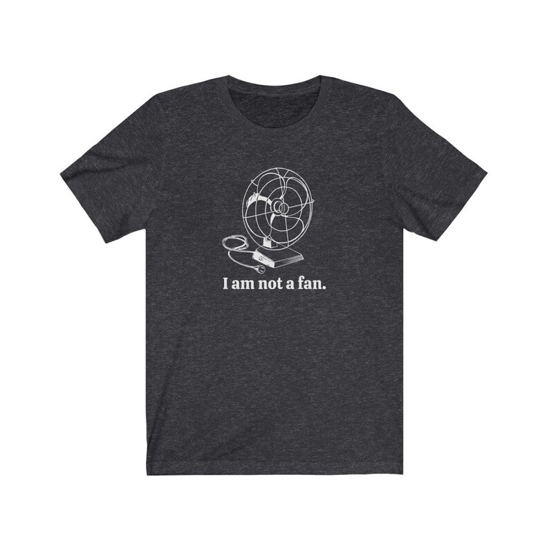 Peut inclure: Un t-shirt gris fonc&eacute; chin&eacute; avec un contour blanc d'un ventilateur vintage et le texte "Je ne suis pas un fan."