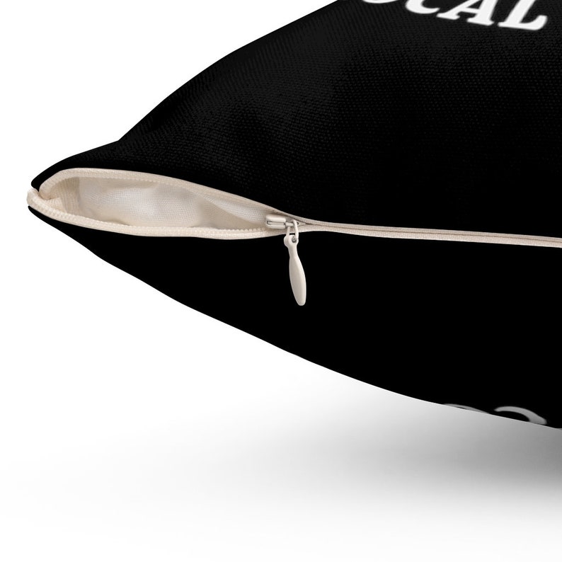 May include: Black pillow with a white zipper and the text "LOCAL" printed on it.