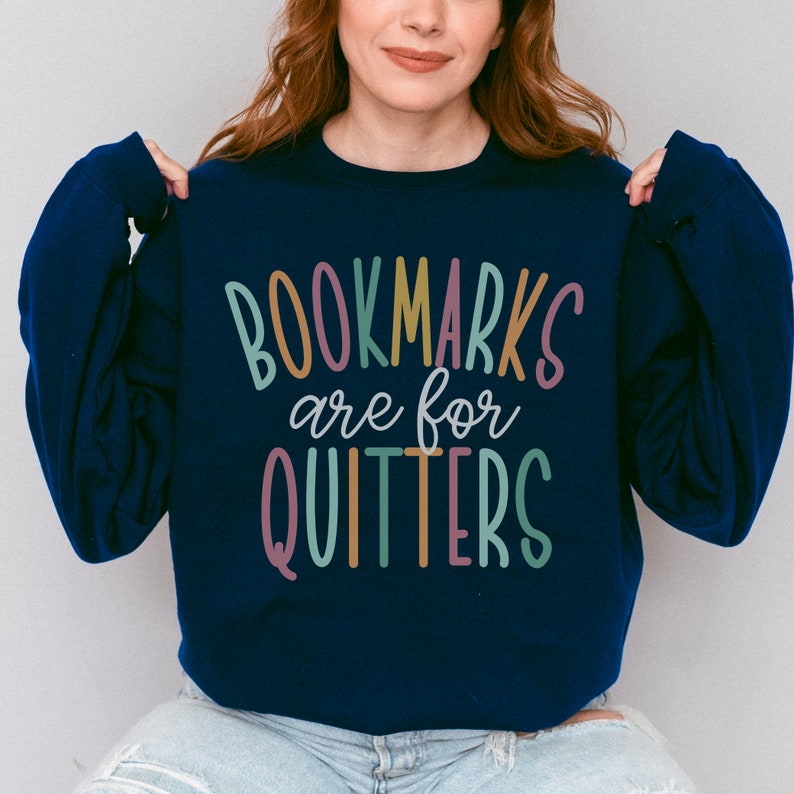 May include: A navy blue sweatshirt with the text "BOOKMARKS are for QUITTERS" in colorful letters.