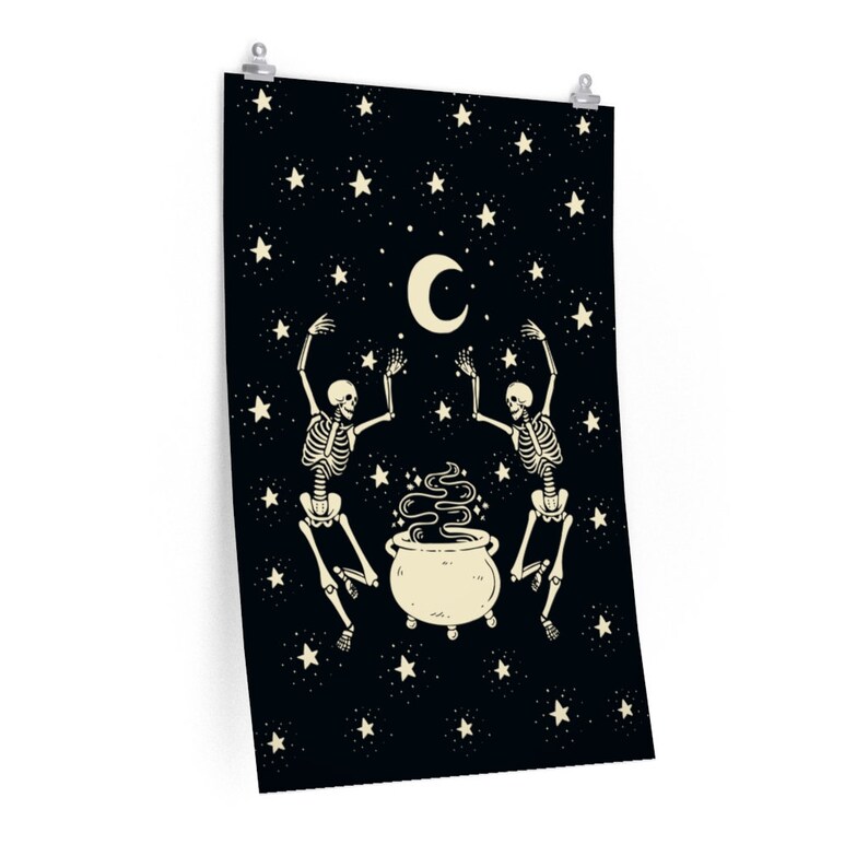 May include: A rectangular wall poster featuring a black background with a cream-colored crescent moon, numerous stars, and two skeletons dancing around a central cauldron emitting swirling smoke. The design is printed on a vertical orientation.