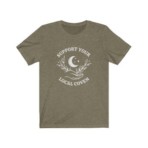 May include: A green t-shirt with a white graphic design that says "Support Your Local Coven" with a crescent moon and floral design.