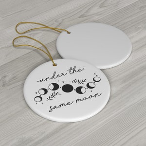 May include: White ceramic ornament with a black and white moon phase design and the text "under the same moon".