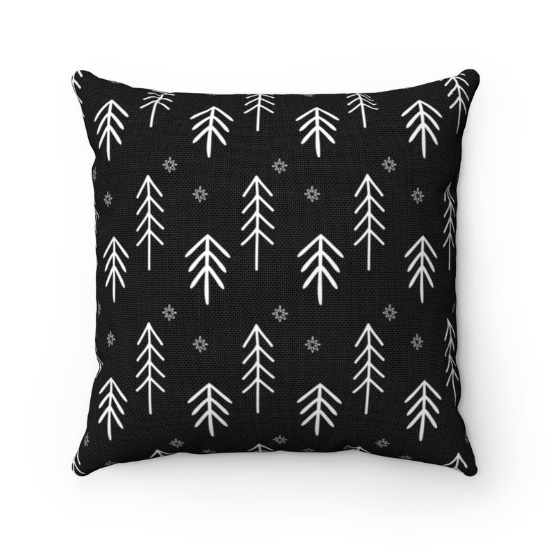 Puede incluir: Coj&iacute;n negro con un patr&oacute;n blanco repetitivo de pinos estilizados y copos de nieve.