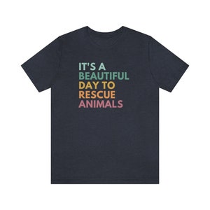 May include: A dark blue t-shirt with the text "It's a beautiful day to rescue animals" in a rainbow gradient.