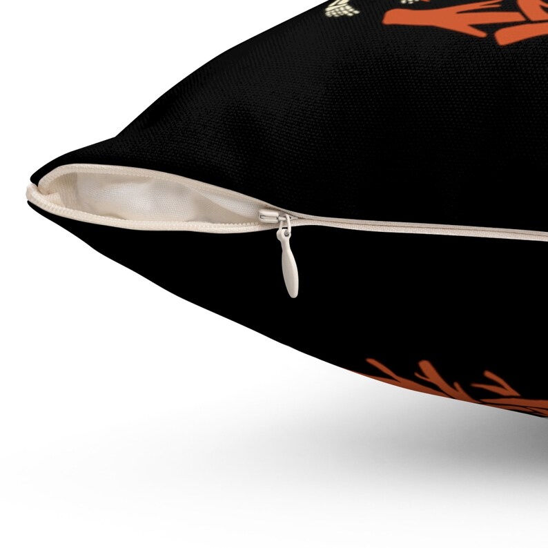 May include: A black pillow with a zipper closure. The pillow has a design of orange and yellow leaves on the front.