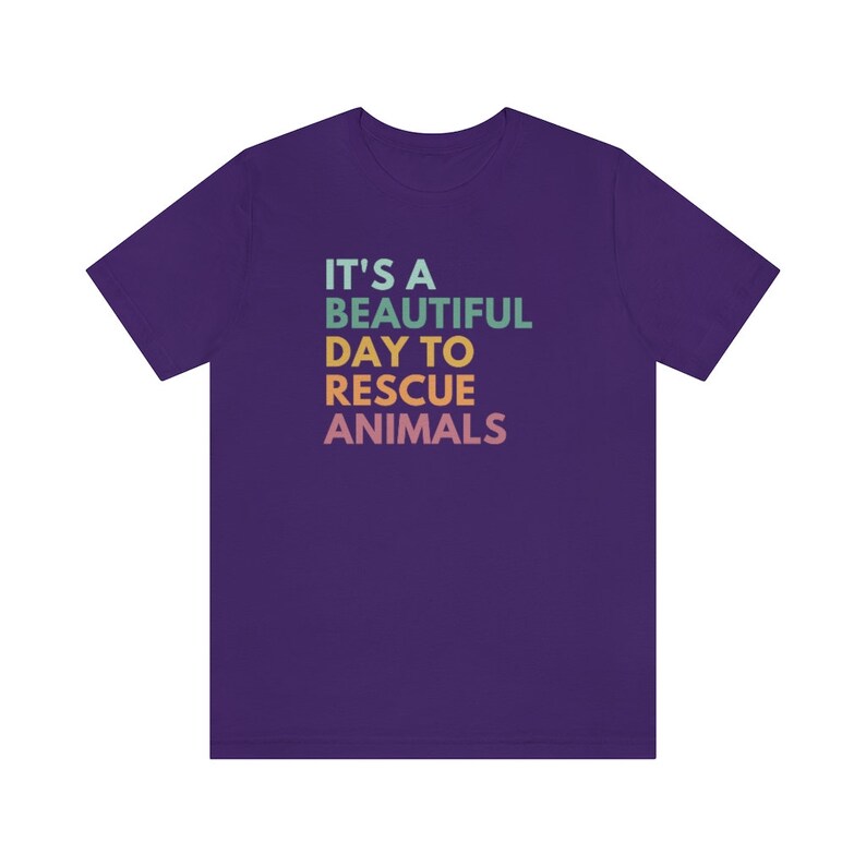 May include: Purple t-shirt with the text "It's a beautiful day to rescue animals" in rainbow colors.