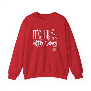Może przedstawiać: Czerwona bluza z białym napisem "IT'S THE little things", ozdobiona małymi sercami. Hasztag #NICU znajduje się pod tekstem. Ten element odzieży jest odpowiedni na r&oacute;żne okazje.