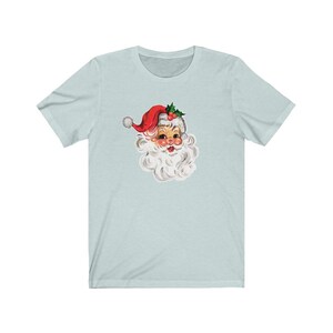 May include: A light blue t-shirt with a vintage illustration of Santa Claus's face. Santa is wearing a red hat with white trim and a white beard.