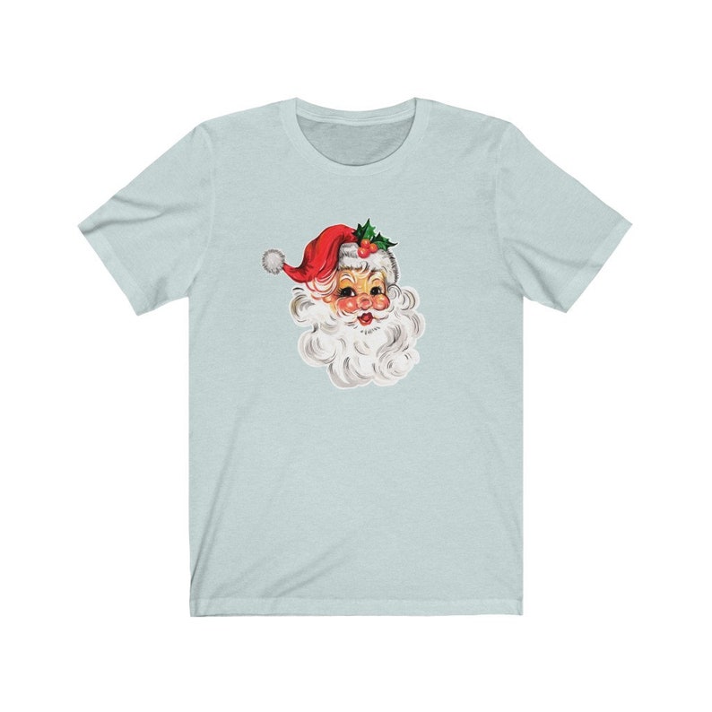 May include: A light blue t-shirt with a vintage illustration of Santa Claus's face. Santa is wearing a red hat with white trim and a white beard.