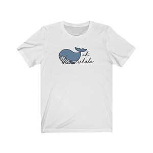 以下が含まれることがあります： 白いTシャツに青いクジラのイラストと黒い文字で「oh whale」と書かれています。
