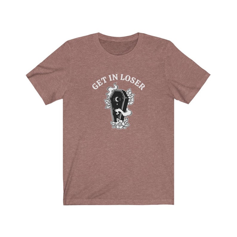 May include: A heather brown t-shirt with the text "GET IN LOSER" in white lettering. A black and white illustration of a coffin with a crescent moon and flowers is below the text.