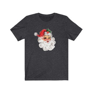 May include: A dark heather grey t-shirt with a vintage illustration of Santa Claus's face. The illustration features a red hat with white trim and a white beard.
