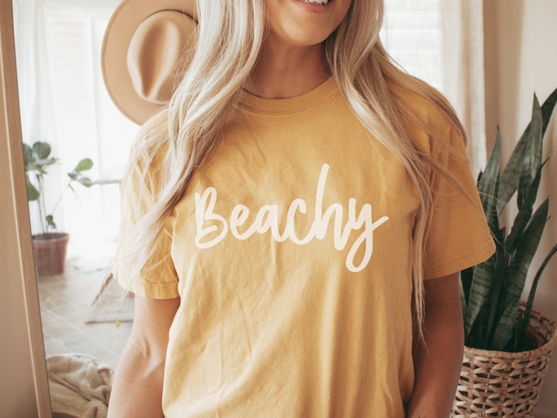 May include: A yellow t-shirt with the word "Beachy" written in white on the front.