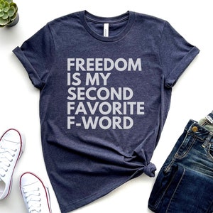 May include: A navy blue t-shirt with the text "FREEDOM IS MY SECOND FAVORITE F-WORD" printed in white.