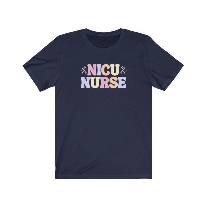 Peut inclure: Un t-shirt bleu marine avec le texte "NICU NURSE" en lettres color&eacute;es. Les lettres sont dans une police de caract&egrave;res de style r&eacute;tro avec un sch&eacute;ma de couleurs rose, jaune et bleu.