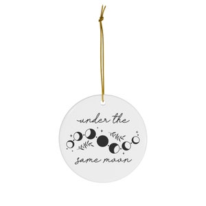 May include: White ceramic ornament with black text and a moon phase design. The text reads "under the same moon".