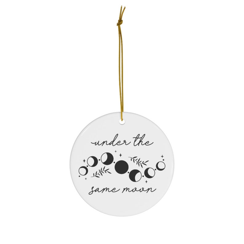 May include: White ceramic ornament with black text and a moon phase design. The text reads "under the same moon".