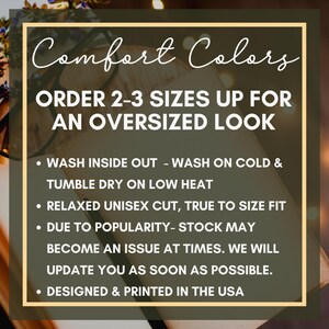 Op de afbeelding: Afbeelding met tekst "Comfort Colors" en "ORDER 2-3 SIZES UP FOR AN OVERSIZED LOOK." Extra tekst bevat wasinstructies, snijdetails en een opmerking over de voorraad. Het ontwerp is gedrukt in de VS.
