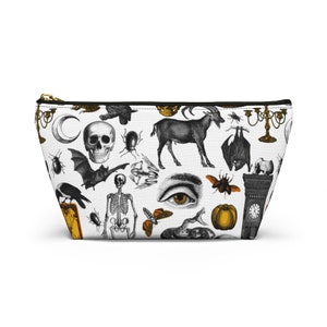 May include: White cosmetic bag with a black zipper and a repeating pattern of vintage Halloween illustrations. The design includes a skull, bat, goat, eye, and other spooky elements. The bag is a trapezoid shape.