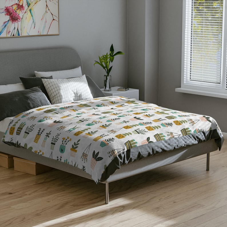 May include: A white bed with a grey headboard and a patterned duvet cover featuring a repeating design of potted plants in various colours and styles. The duvet cover is made of a soft, comfortable fabric and is perfect for adding a touch of nature to any bedroom.