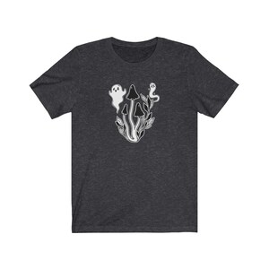Puede incluir: Una camiseta gris oscuro jaspeada con un gr&aacute;fico blanco de fantasmas y setas. El gr&aacute;fico representa tres setas con tres fantasmas flotando sobre ellas.