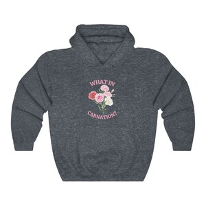 Peut inclure: Un sweat &agrave; capuche gris fonc&eacute; avec un motif rose d'un bouquet d'&oelig;illets et le texte "WHAT IN CARNATION?"