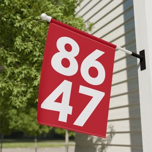 May include: Red house number flag with white numbers 86 and 47. The flag is attached to a white pole and is hanging from a white house.