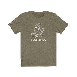 Peut inclure: Un t-shirt vert avec un contour blanc d'un ventilateur et le texte "Je ne suis pas un fan."