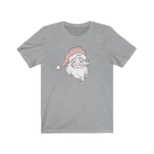 May include: A heather gray t-shirt with a vintage-style illustration of Santa Claus's face. The illustration is in shades of gray and pink.