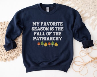 May include: Navy blue sweatshirt with the text "My favourite season is the fall of the patriarchy" and a row of five stylised trees in autumn colours.
